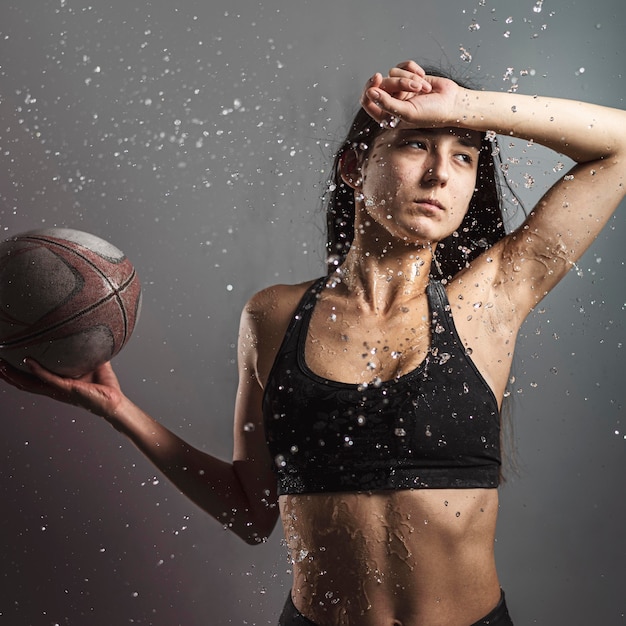 Front view of wet female rugby player holding ball