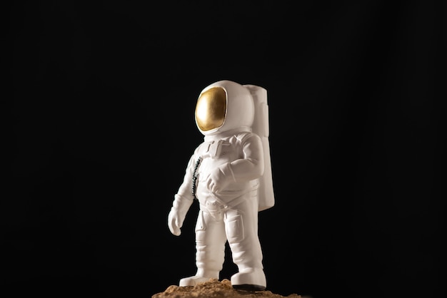 Front view of white astronaut around stones on black
