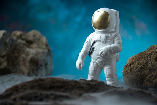 Free photo front view of white astronaut with rocks on moon blue desk death sci fi funeral