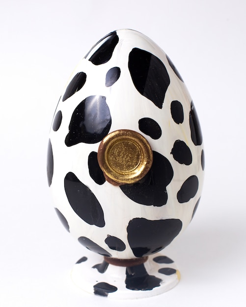 スタンドにゴールドシールが付いた正面の白と黒のチョコレートの卵の色