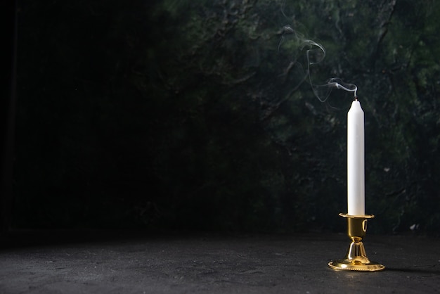 Free photo front view of white candle in golden stand on black