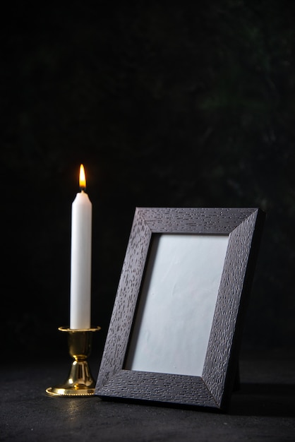 Free photo front view of white candle with picture frame on dark