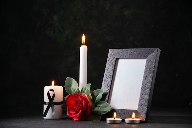 Free photo front view white candle with picture frame and flower on dark desk funeral evil death