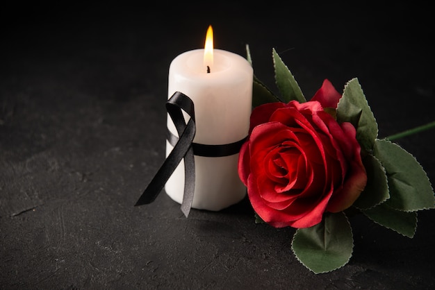 Front view of white candle with red rose on black