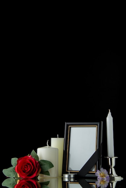Vista frontale di candele bianche con cornice sulla parete nera