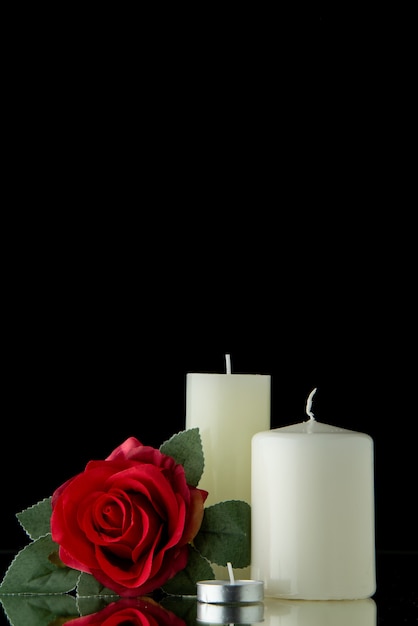 검은 벽에 붉은 꽃과 흰색 촛불의 전면보기