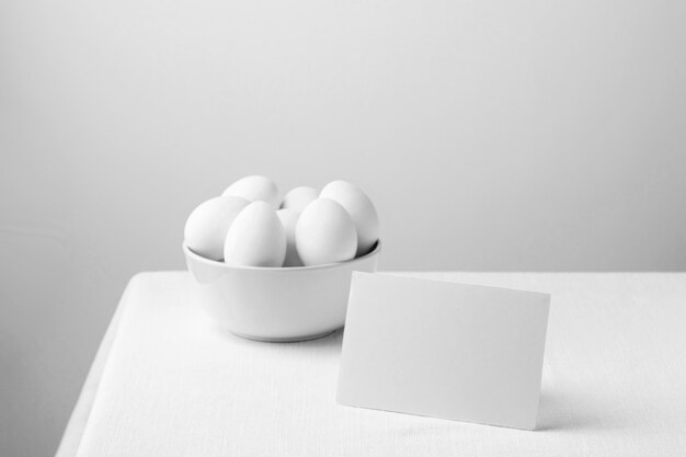 Front view white chicken eggs in bowl with blank note