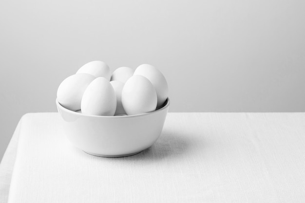 Front view white chicken eggs in bowl with copy-space