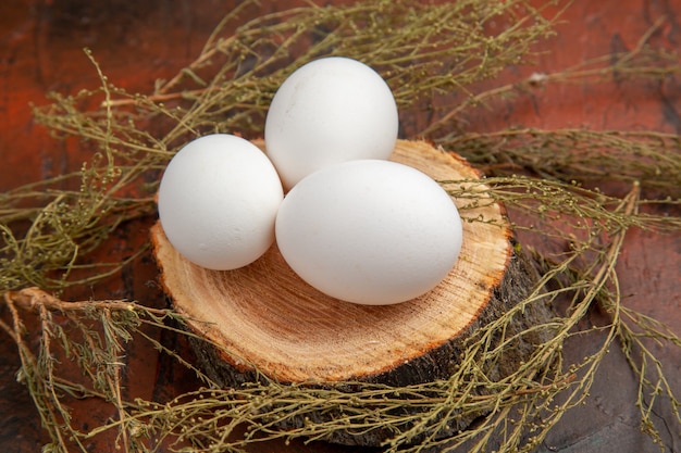 Front view white chicken eggs on dark surface