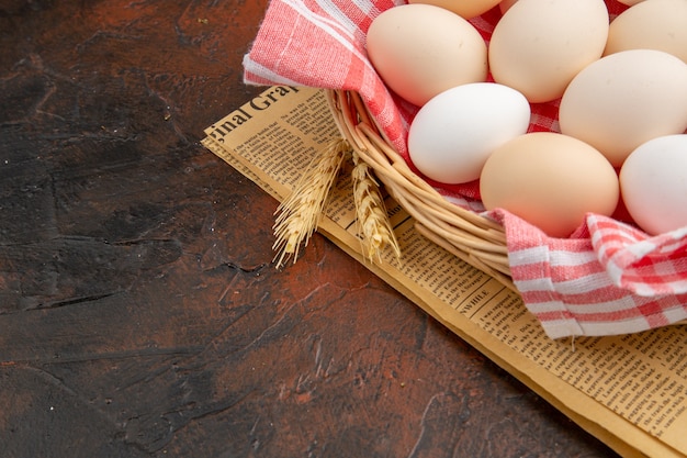 Front view white chicken eggs inside basket with towel on dark surface