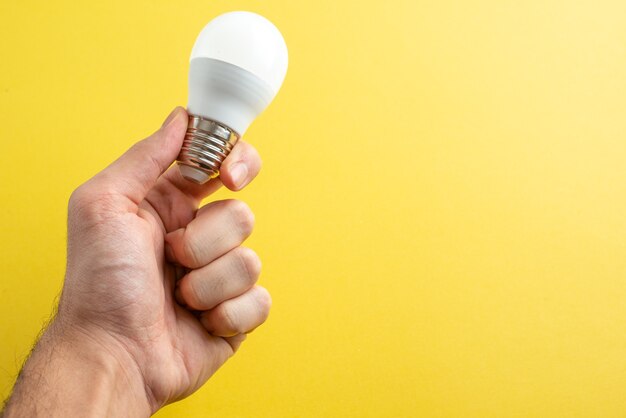 Front view white lightbulb on male hands on yellow background color light photo electricity house room human