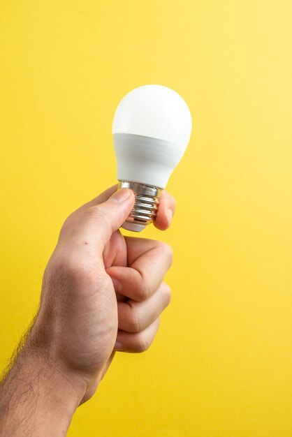 Front view white lightbulb on male hands on yellow background paper color photo drawing notepad school college