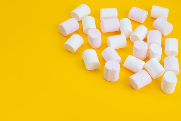 A front view white marshmallows delicious goodies on yellow desk, sugar sweet candy color