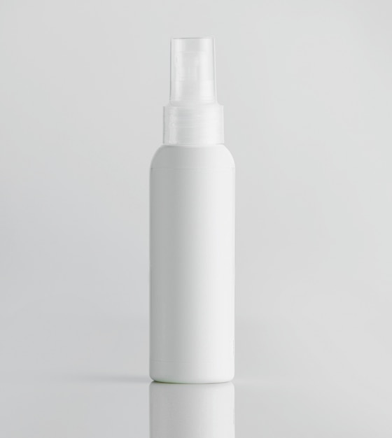 Front view white plastic bottle with sprayer on a white wall