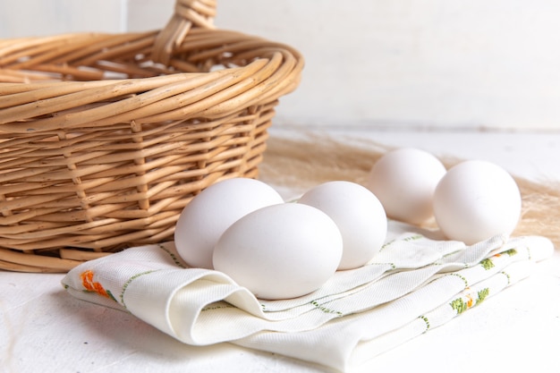 Front view white whole eggs with basket on the white background.