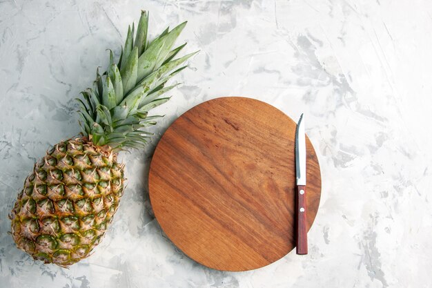 Вид спереди на весь свежий золотой ананас и нож для разделочной доски на мраморной поверхности стола