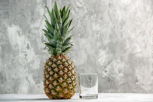 Front view of whole fresh golden pineapple and glass on table