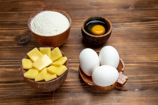 正面図茶色の木製テーブル製品の卵生地ペストリーにチーズ粉と生卵全体