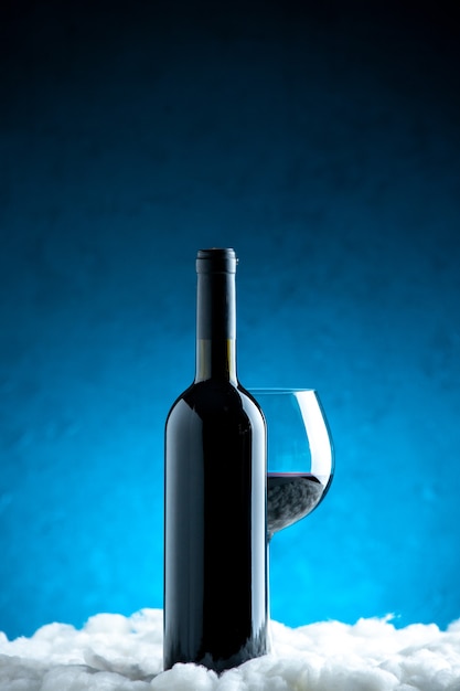 Foto gratuita bicchiere e bottiglia di vino vista frontale su sfondo blu