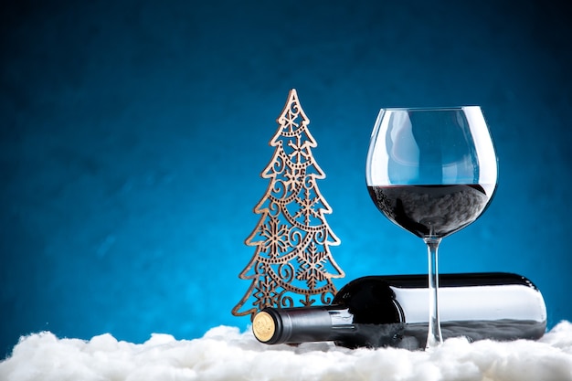 Foto gratuita bicchiere da vino vista frontale e bottiglia orizzontale su sfondo blu