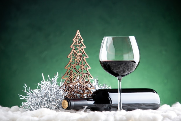 Front view wine glass and bottle horizontal xmas detail on green background