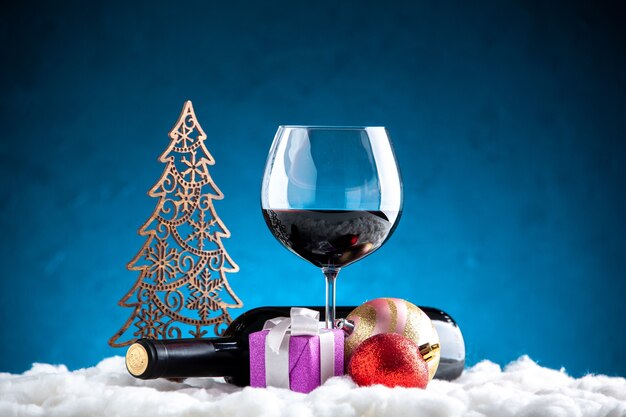 Вид спереди бокал для вина и бутылки горизонтальные рождественские детали на синем фоне