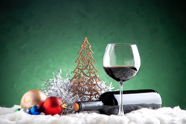 Front view wine glass and bottle horizontal xmas details on green background
