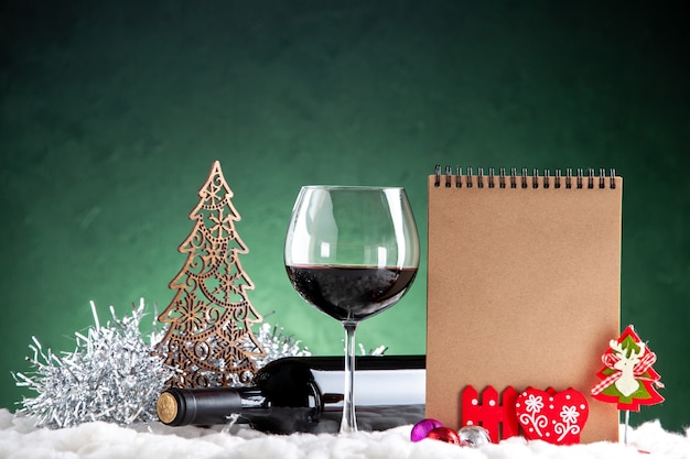 Free photo front view wine glass and bottle horizontal xmas details on green background