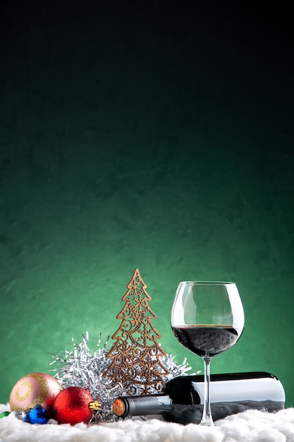 Front view wine glass and bottle horizontal xmas tree toys on green background