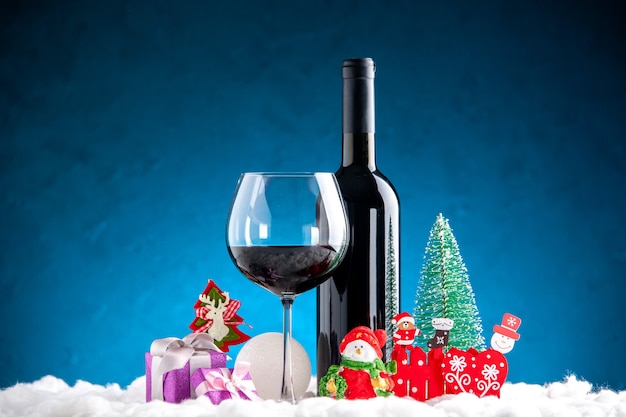 Free photo front view wine glass and bottle xmas details on blue background