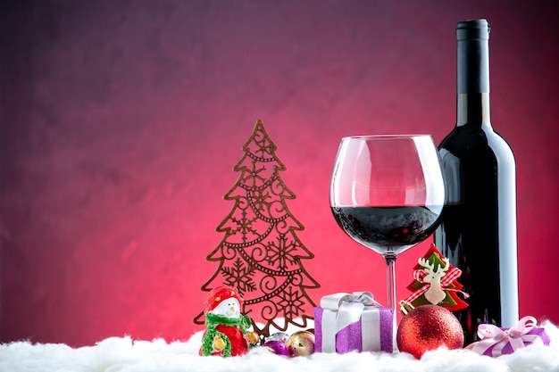Front view wine glass and bottle xmas details on dark red background