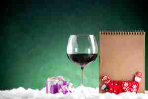 Free photo front view wine glass small gifts notepad on green background