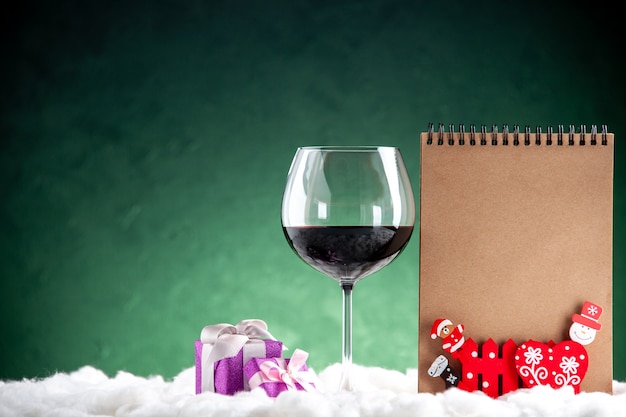 Вид спереди бокал для вина маленькие подарки блокнот на зеленом фоне