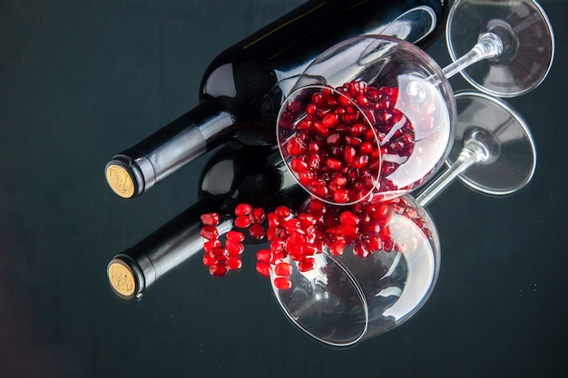 Bicchiere di vino vista frontale con melograni sbucciati sulla superficie scura