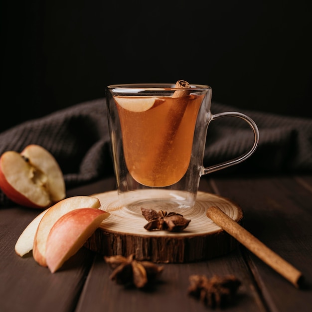 Зимний горячий напиток в стакане с яблоком и корицей, вид спереди