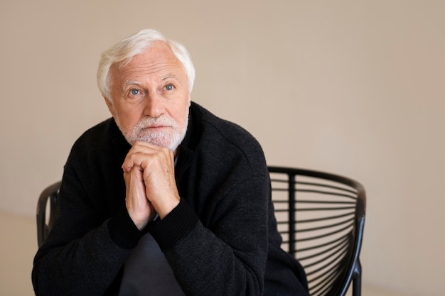 Free photo front view wise senior man posing indoors