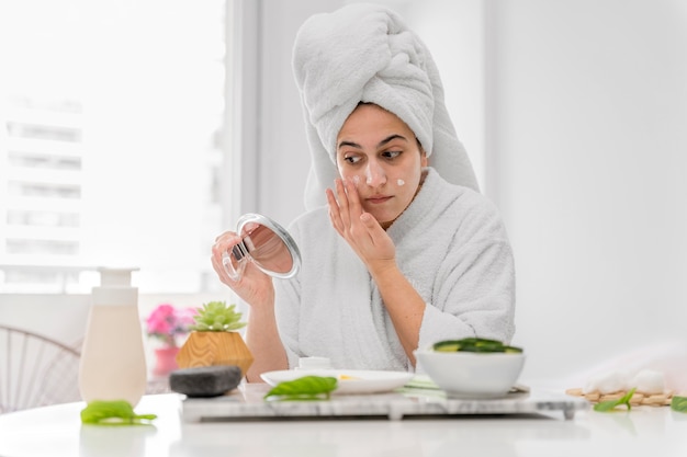 Free photo front view woman applying face cream