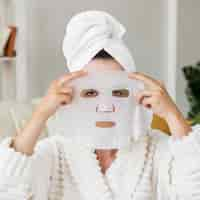 Free photo front view woman applying facial mask