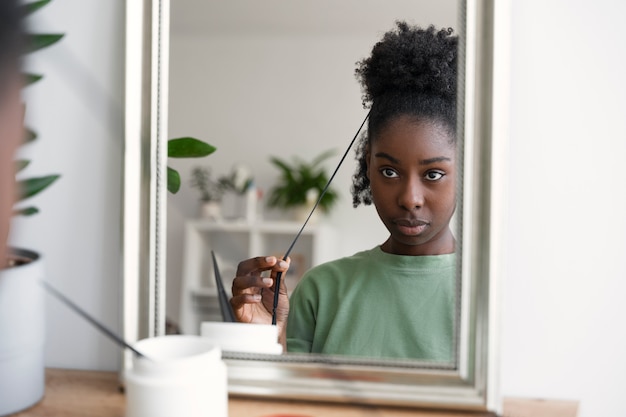 Front view woman arranging hair in mirror