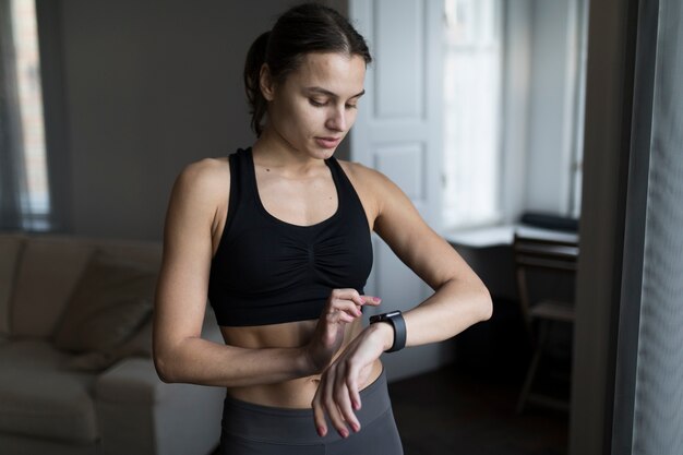 Front view of woman in athleisure looking at her smartwatch