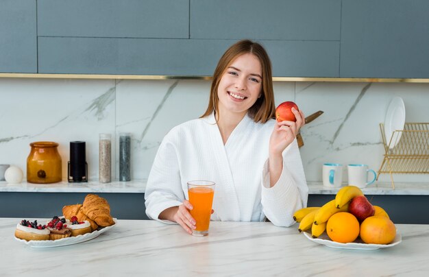 Front view of woman in bathrobe holding apple