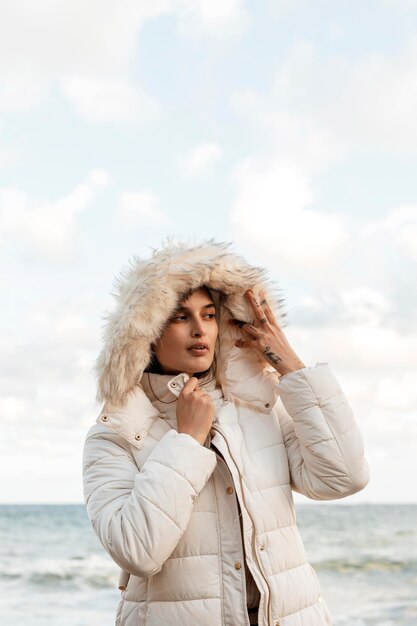 Front view of woman at the beach with winter jacket and copy space