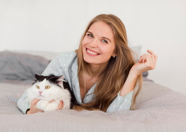 Front view of woman in bed with pajamas and cat