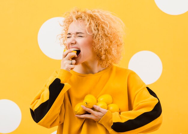 Front view of woman biting from lemon