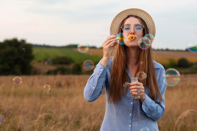 Front view of woman blowing bubbles outdoors in nature