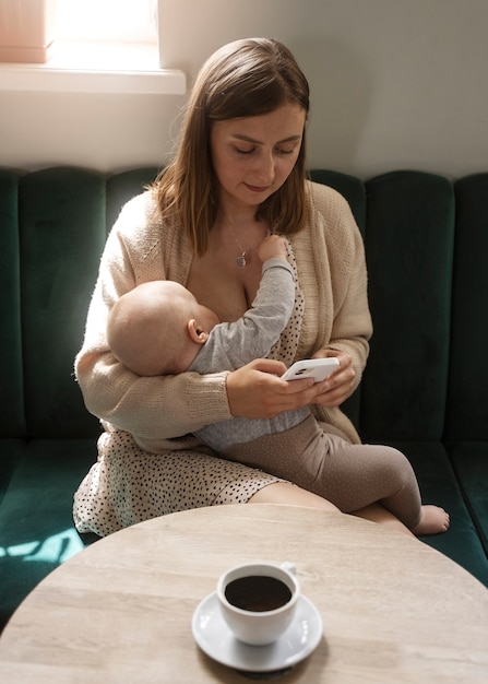 屋内で赤ちゃんを母乳で育てる正面図の女性