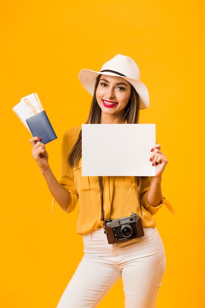 Front view of woman carrying a camera and holding plane tickets and passport