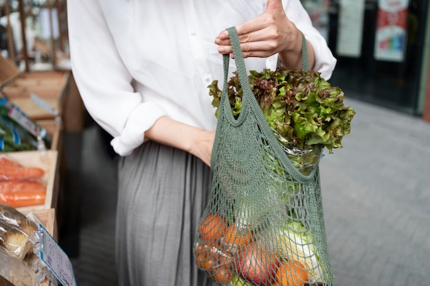 Foto gratuita donna di vista frontale che trasporta generi alimentari in borsa