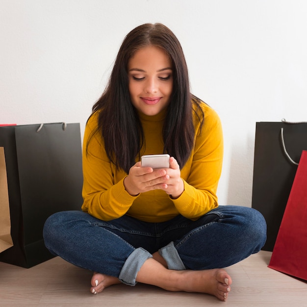 Foto gratuita donna di vista frontale che controlla il suo telefono sul divano