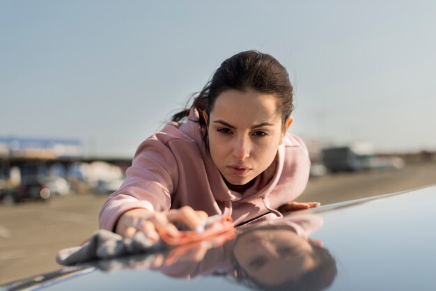 Front view woman cleaning the hood on the car